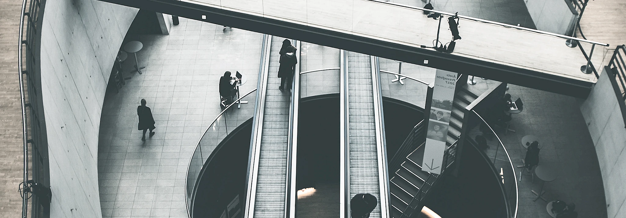 Hallin Löfgren Juristbyrå AB - En vy av människor som går nerför en rulltrappa i ett centrum.