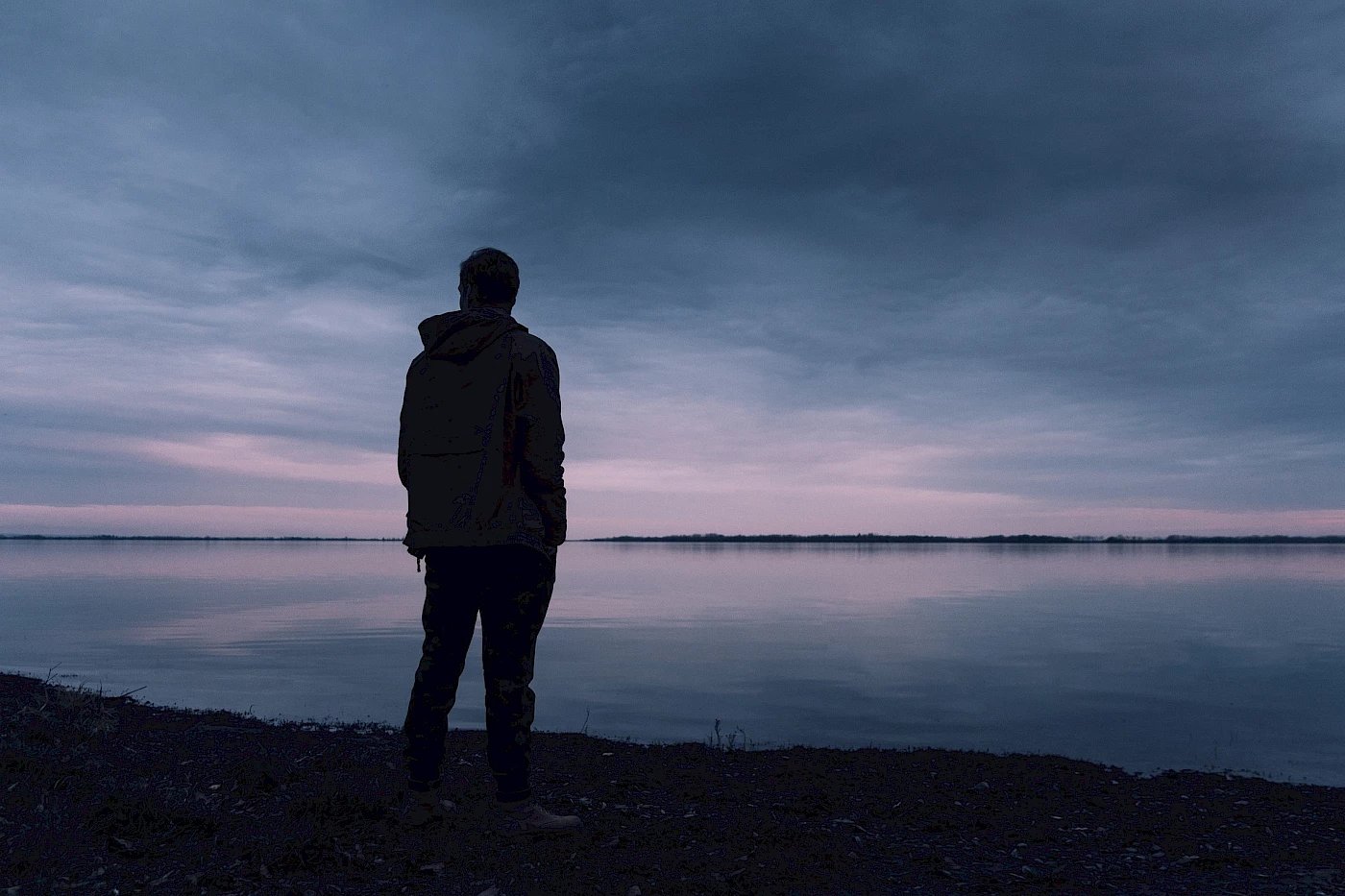Hallin Löfgren Juristbyrå - En man står vid en strand och tittar upp mot himlen.